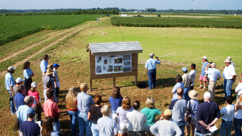 Group of people gathered in front of a sign at Cherry Research Farm