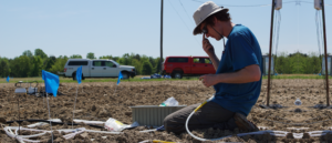 person kneeling on ground using agricultural equipment