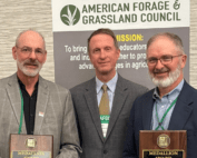 Three men holding awards in front of a banner that reads American Forage and Grasslands Council