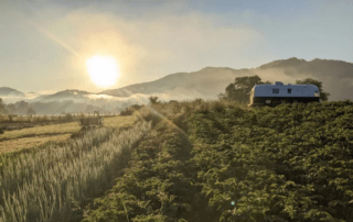 sun setting behind mountains in background, farm field in foreground