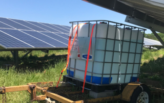 A large tank being moved in between two solar panels