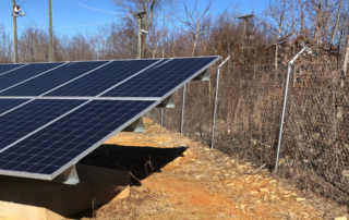 One large solar panel taking up the whole left of the photo. To the right is a fence and behind the fence and in the background are barren trees