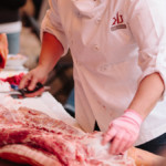 person cutting large slab of meat