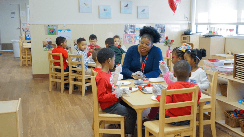 Shironda Brown at table with children showing them fruit activity
